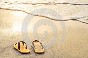 Yellow flip flop on the beach with bright light of sunset in summer