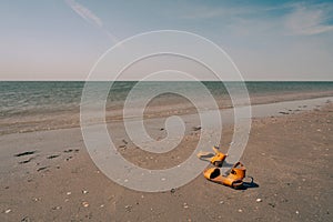 Yellow flip flop on the beach. Summer holidays concept. Sandals, sand, sea, blue sky with bright light of sunset in summer