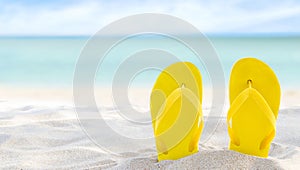 Yellow flip flops on beach sand texture and tropical sea background. Summer holidays and hot season. Fun ocean weekend. Summertime photo