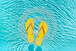 Yellow Flip Flops floating in a clear blue swimming pool water