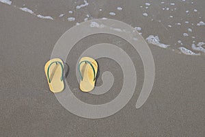Yellow flip-flops footware pair on the beach sand photo