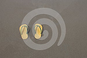 Yellow flip-flops footware pair on the beach sand photo