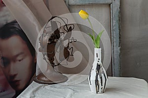 Yellow flower in Black and White Handmade ceramic vase and Vintage fan on white textured table cloth in front of Classic chinese