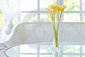 Yellow flower in vase on table and window sill background. Vintage style decorate