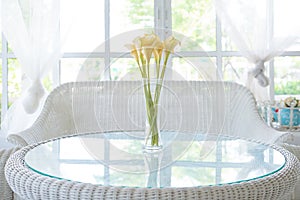 Yellow flower in vase on table and window sill background. Vintage style decorate photo