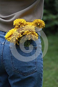 Yellow flowers in back pocket of woman blue jeans