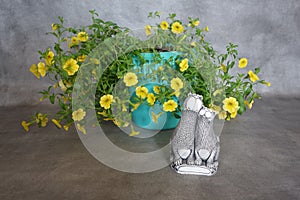 Yellow flowers in a blue pot and a cat figurine