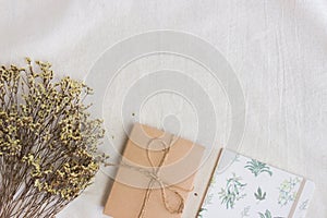 Yellow flowers with brown gift box and notebook over the white fabric.
