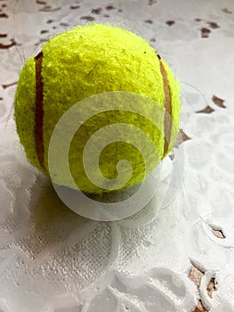 Yellow fluffy tennis ball for playing tennis lies on a table on the background of a white tablecloth