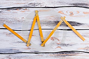 Yellow folding ruler on wooden background.