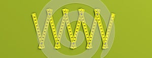 Yellow folding wooden ruler isolated cutout on green background, banner. 3d illustration