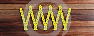 Yellow folding wooden ruler isolated cutout on wooden background, banner. 3d illustration