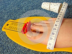 Yellow foot measurement device with naked foot upon with measuring tape