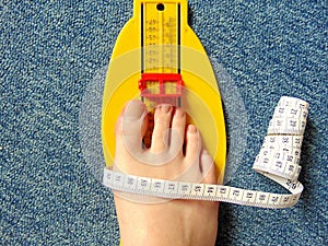 Yellow foot measurement device with naked foot upon with measuring tape