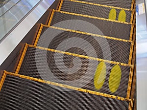 Yellow footprints on escalator steps, standing position symbol for people keep distanceyellow footprints on escalator steps, stand