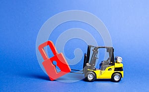 A yellow forklift tilts a red padlock from the road. Bypassing prohibitions and sanctions restrictions, lobbying the interests