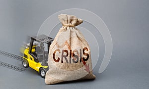 Yellow forklift truck can not lift the bag with the inscription crisis. Economic crisis, stagnation and recession of the economy. photo