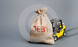 Yellow forklift truck can not lift the bag with the inscription debt. Inability to repay a loan, debt restructuring. High business