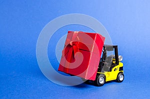 Yellow forklift truck carries a red gift box with a bow. Purchase and delivery of a present. retail, discounts and contests. photo