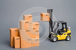 Yellow Forklift truck raises a cardboard box to the top of a stack pile of boxes. Warehouse, stock. commerce, retail. E-commerce