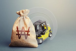 Yellow forklift unable to lift a south korean won money bag. Interest rate. Stimulating economy. Helicopter money, subsidies soft