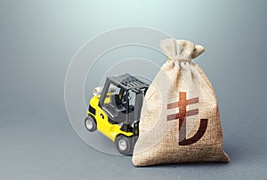 Yellow forklift unable to lift a turkish lira money bag. Interest rate. Strongest financial assistance, support of business and