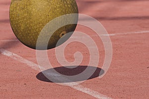 Yellow four square playground ball bouncing on red court with shadow. Exercise, fitness and fun concept