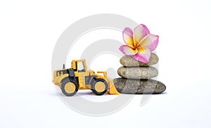 Yellow front loader truck with flower on stone isolate on white background