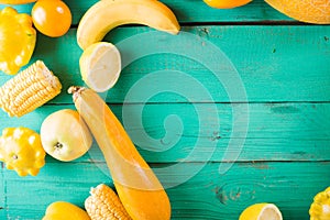 Yellow fruits and vegetables on a turquoise wooden background. Colorful festive still life.