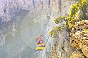 Yellow Funicular Cable with cabin high with Rocky Mountains on background