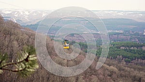 yellow funicular car with passengers moves by cableway.