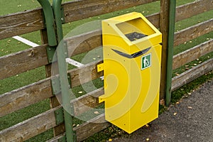 Yellow garbage bin hanging on the fence