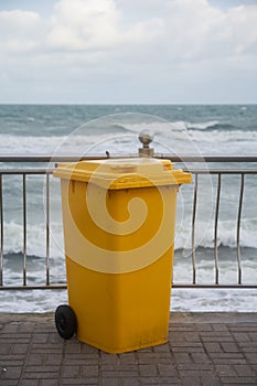 Yellow garbage container by the sea .