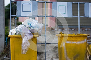 yellow Garbage Trash Bin full of garbage in small village