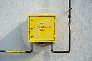 Yellow gas control box on grey house wall