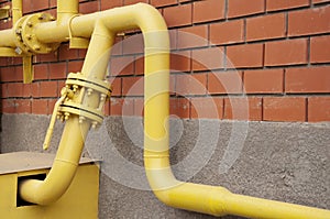 Yellow gas pipe against a red brick wall.