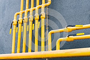 Yellow gas pipe with a crane goes along the facade of a new multi-storey building