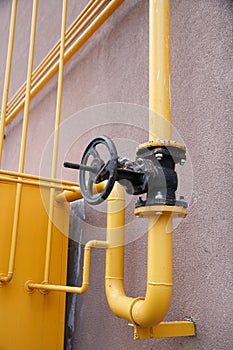 Yellow gas pipe with a crane goes along the facade of a new multi-storey building. House connected to gas for domestic use