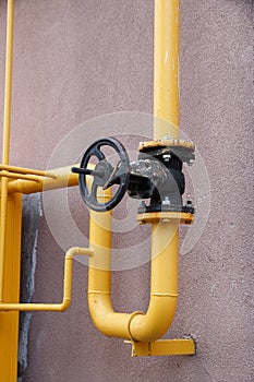 Yellow gas pipe with a crane goes along the facade of a new multi-storey building. House connected to gas for domestic use