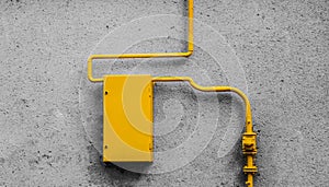 A yellow gas pipe and a distribution board on a gray wall
