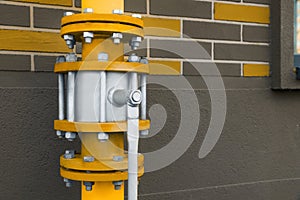 Yellow gas pipe with valve near brick wall outdoors, space for text