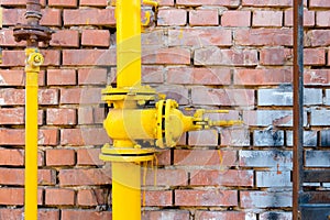 Yellow gas pipe and valve on red brick wall, copyspace