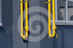 Yellow gas pipe with a vent on the facade of a multi-storey building. Natural gas for domestic household use, gas pipe line