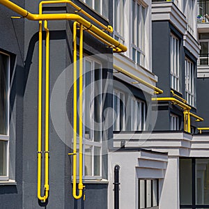 Yellow gas pipe with a vent on the facade of a multi-storey building. Natural gas for domestic household use, gas pipe line