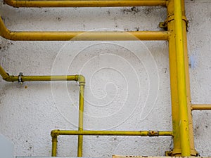 Yellow gas pipes on old dirty building wall