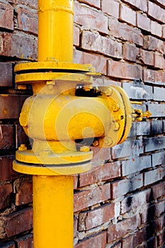 Yellow gas valve over red brick wall