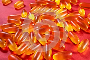 yellow gelatin capsules on a red background. omega viramins  close-up  macro