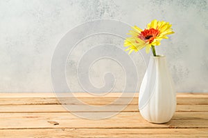 Yellow gerbera flower in vase on wooden table