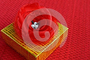 Yellow gift box with red fabric flower decoration close up