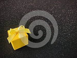 Yellow gift box with ribbon bow on the black Starlight background.